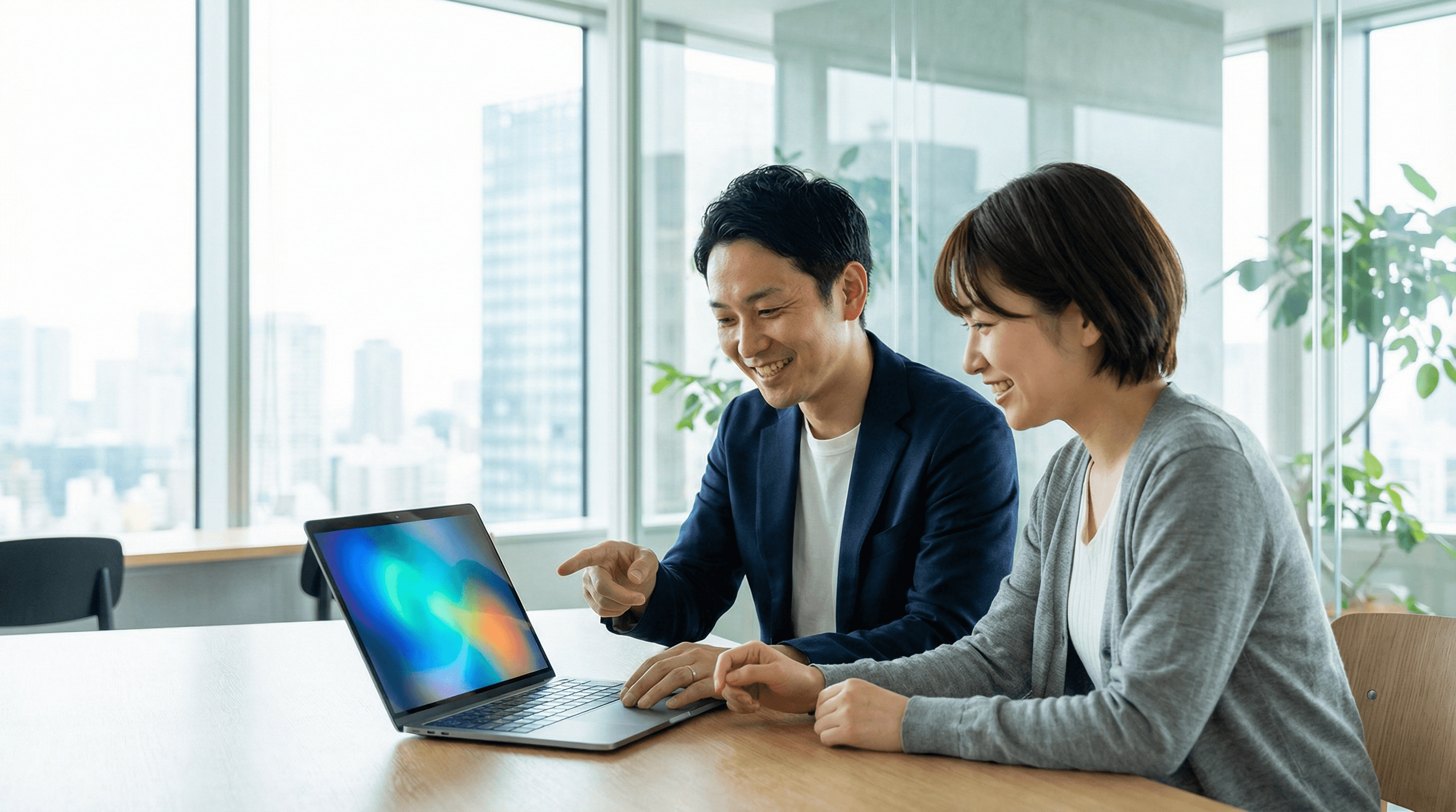 サポート担当者がクライアントとPC画面を囲んで笑顔で打ち合わせしている